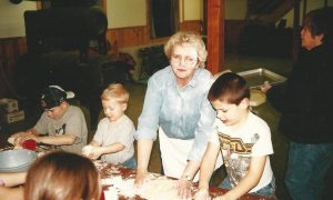 woman with flour on her face baking with kids