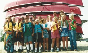 group of students in life jackets by canoes