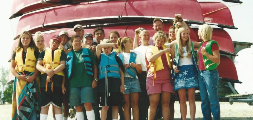 group of students in life jackets by canoes